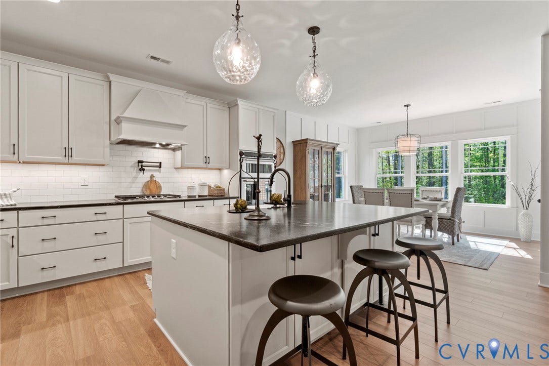 9143 Terroir Lane, Villas, New Kent, VA 23124 Open-concept kitchen featuring an eat-at island, white cabinetry, integrated oven, and wood-finish flooring