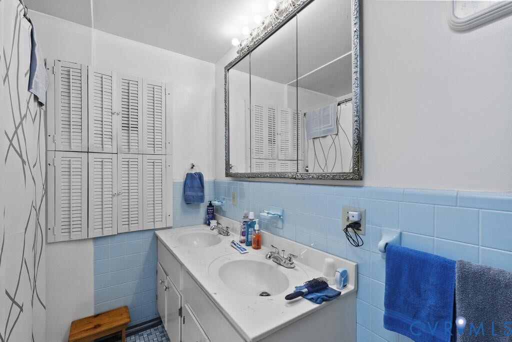 21 Vanderpool Lane, Detached, Cumberland, VA 23040 Dual vanity with integrated sinks, tiled backsplash, wall-mounted medicine cabinet with ornate frame, and louvered built-in cabinetry