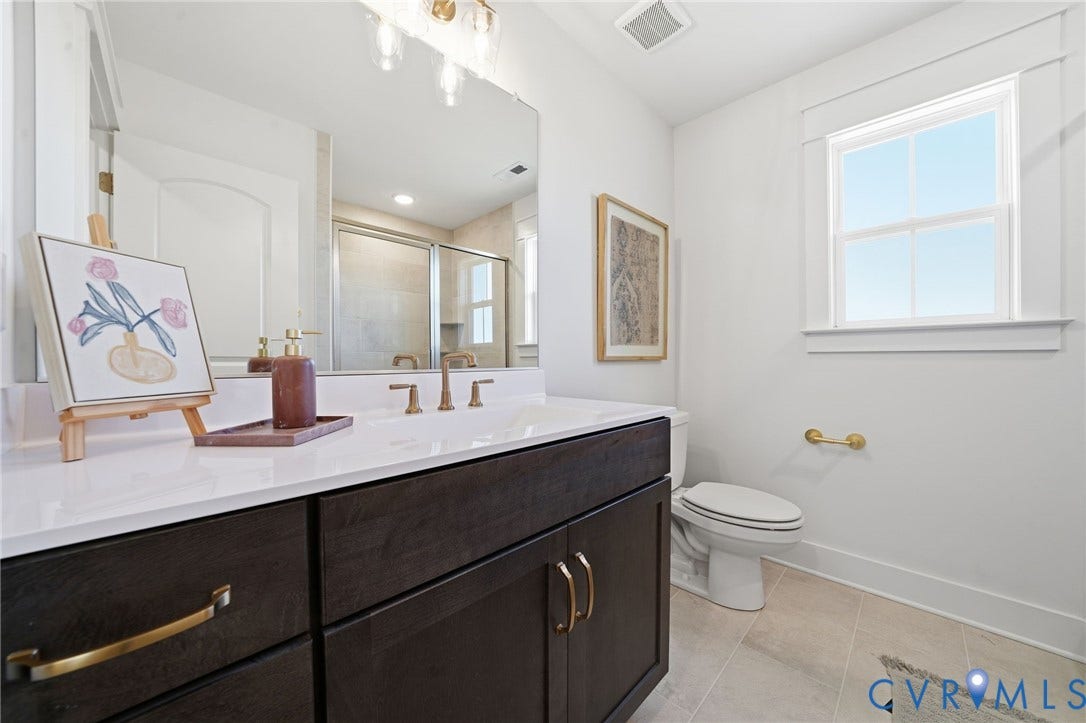 9169 Terroir Lane, Villas, New Kent, VA 23124 Dark wood vanity with gold-finish hardware, white countertop, and large vanity mirror