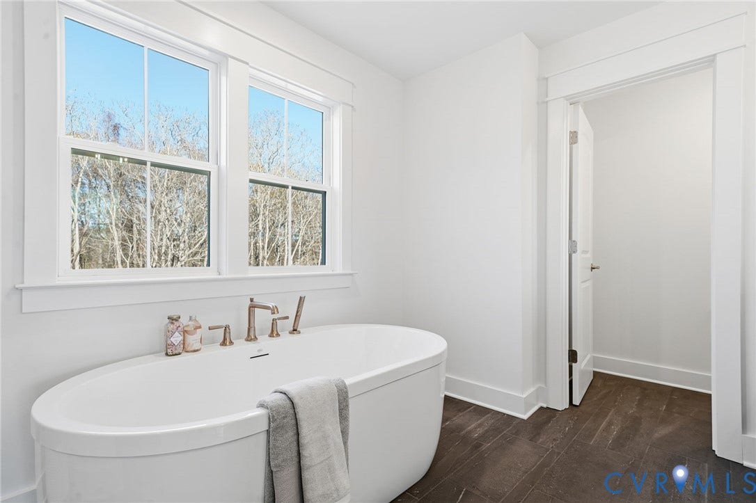 9169 Terroir Lane, Villas, New Kent, VA 23124 Freestanding soaking tub with brushed brass fixtures, large windows, and dark wood-finish flooring
