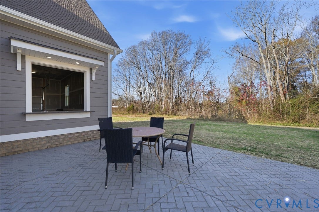 9169 Terroir Lane, Villas, New Kent, VA 23124 Expansive paver patio with a herringbone pattern, featuring an exterior pass-through window with accent lighting, and a stone veneer foundation