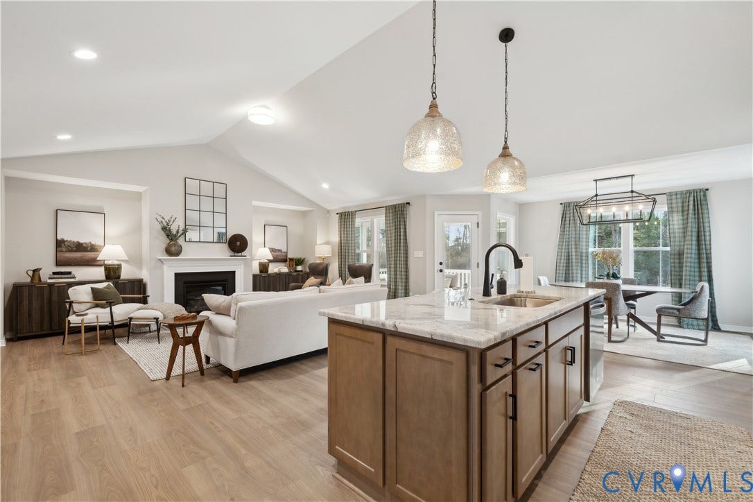 9102 Terroir Lane, Viniterra Villas, New Kent, VA 23124 Open-concept living space featuring wood-finish flooring, a kitchen island with stone countertop, recessed lighting, and a fireplace with a mantel