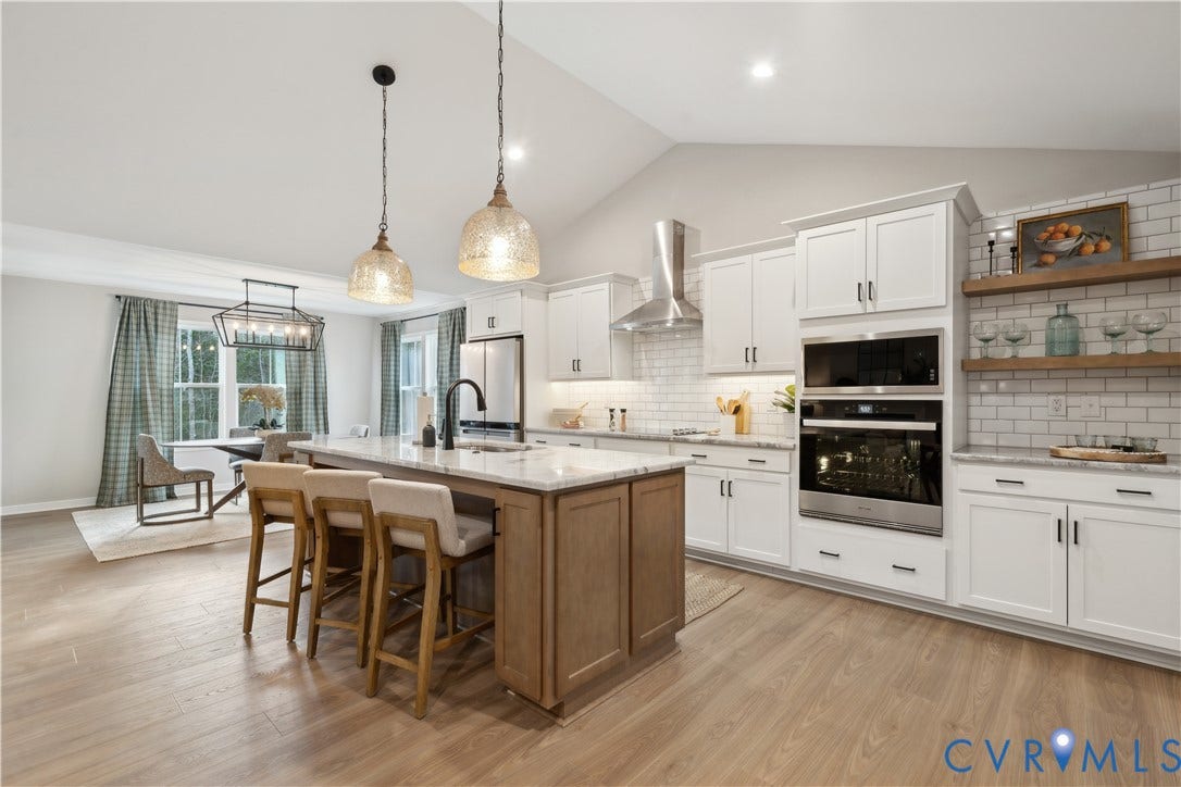 9102 Terroir Lane, Viniterra Villas, New Kent, VA 23124 Vaulted ceiling, wood-finish flooring, white shaker cabinetry, built-in stainless steel appliances, and a large central island with seating