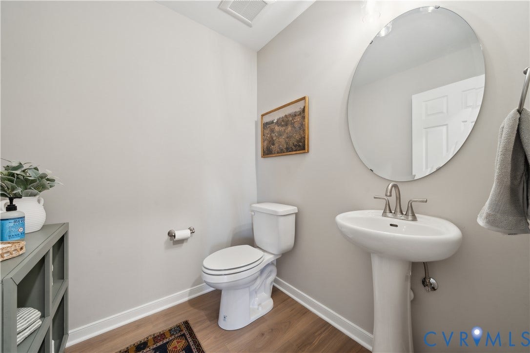 9102 Terroir Lane, Viniterra Villas, New Kent, VA 23124 Pedestal sink with brushed nickel faucet, oval mirror, and toilet