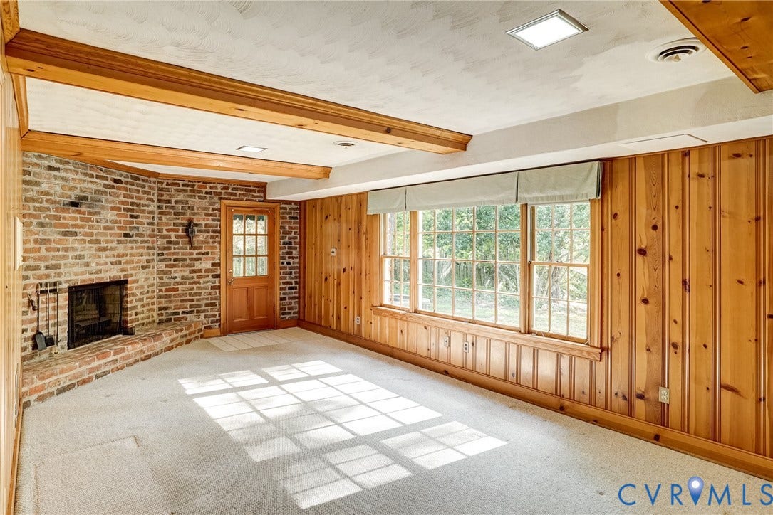 1407 W Monmouth Court, Henrico, VA 23238 Lower level family room with exposed brick fireplace with a raised hearth, wood paneling and exposed wood ceiling beams. Plus fantastic view of the backyard!