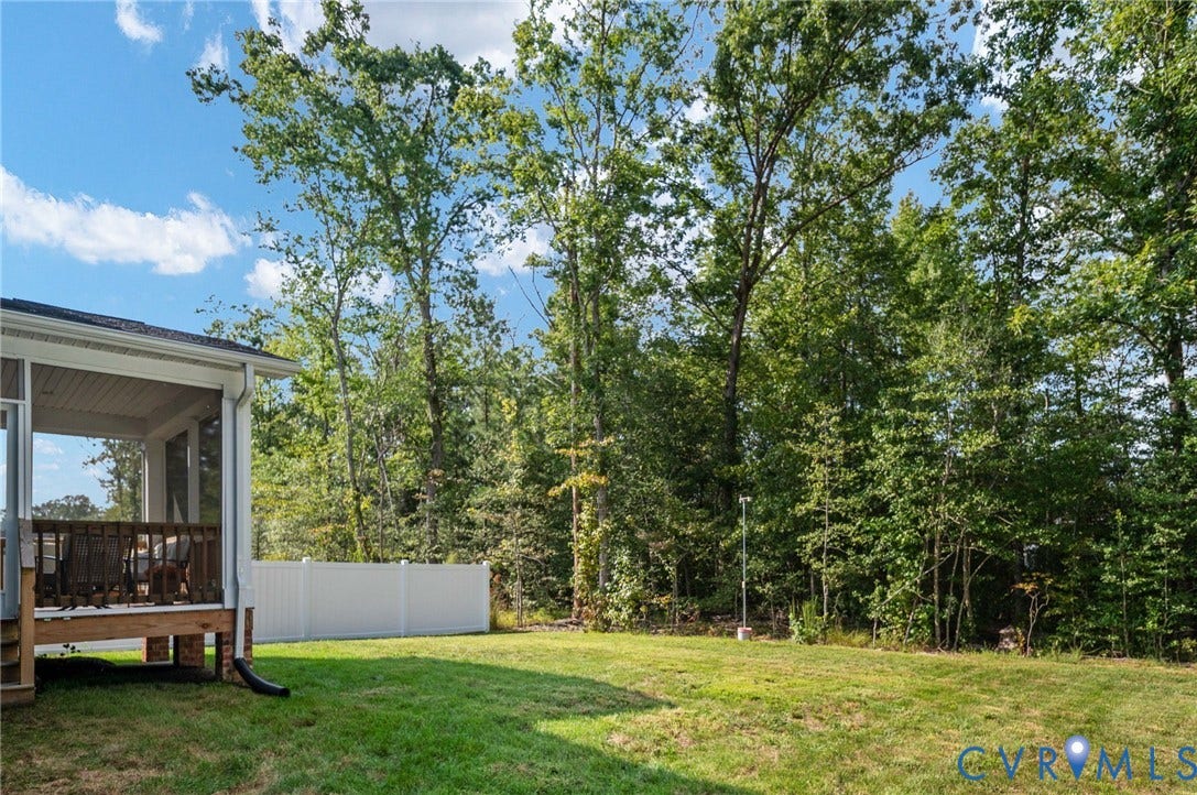 1961 Enon Station Drive, Chester, VA 23836 Expansive backyard featuring a manicured lawn, screened porch, and privacy fencing, bordered by mature trees