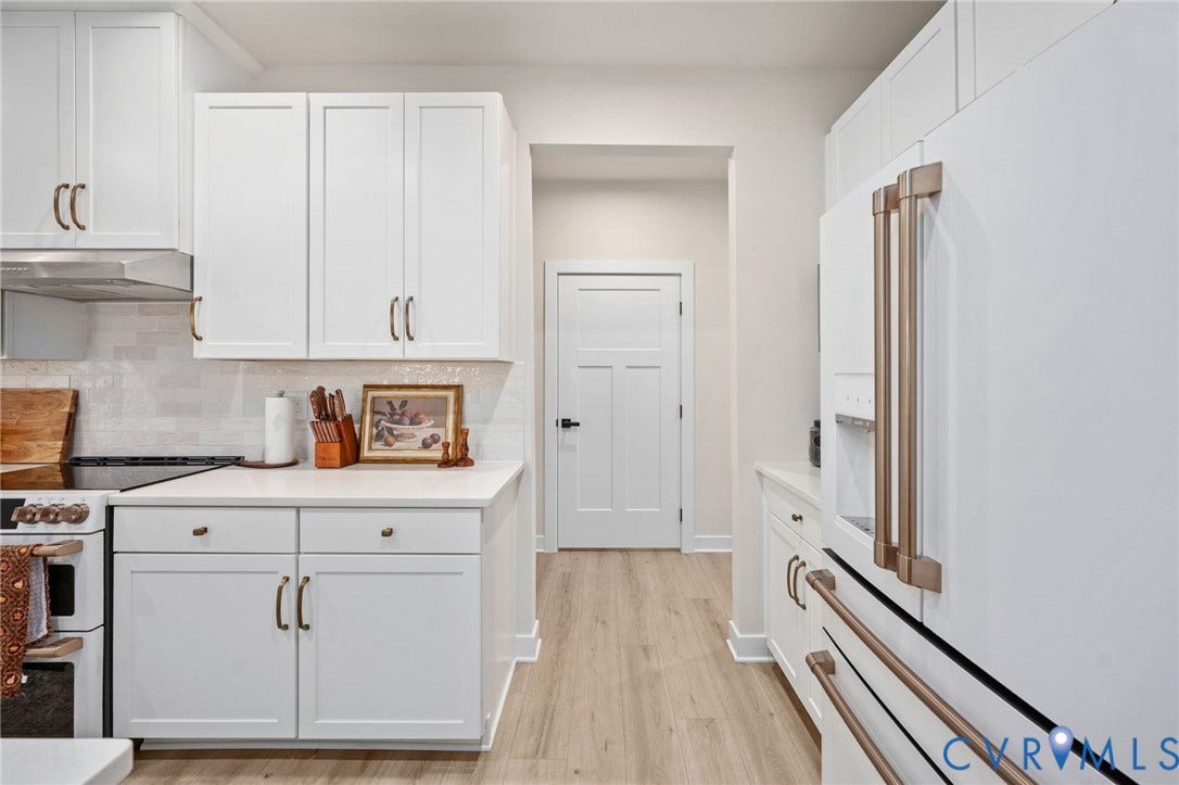 1961 Enon Station Drive, Chester, VA 23836 White shaker cabinetry with gold-tone hardware, white countertop, stainless steel range hood, and wood-finish flooring