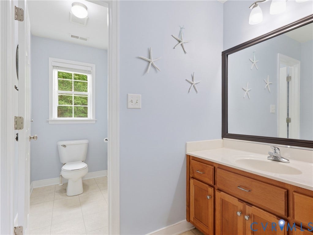8325 Caroline Vines Way, Estates At Willis Church, Henrico, VA 23231 Powder room with a single window, white toilet, tiled flooring, wood-finish vanity with a single sink, and a framed mirror