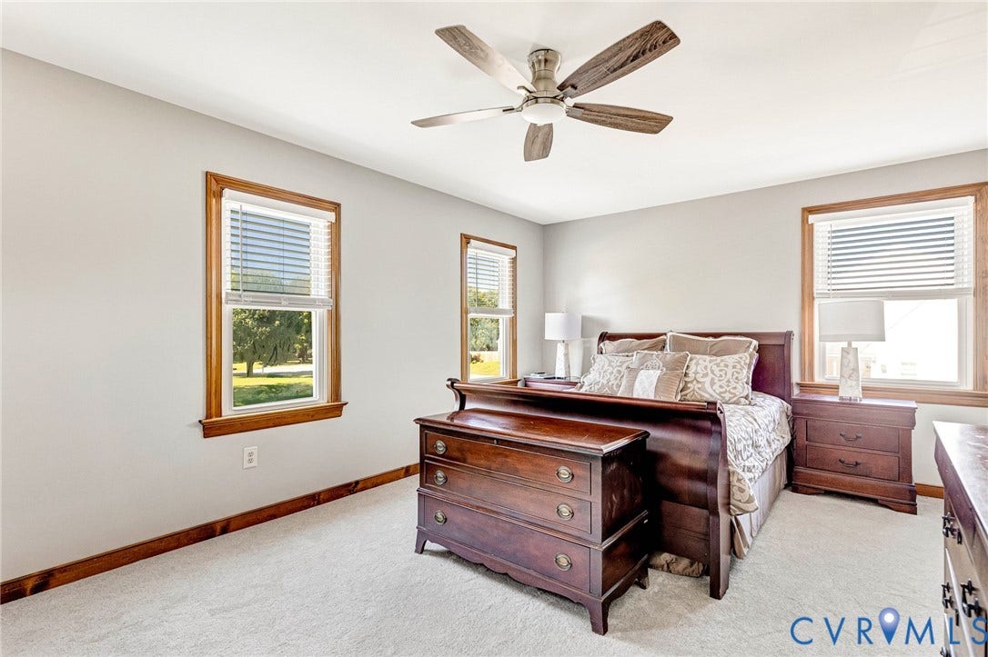 Recessed lighting, ceiling fan with light fixture, two windows with wood trim, and light-toned carpeting