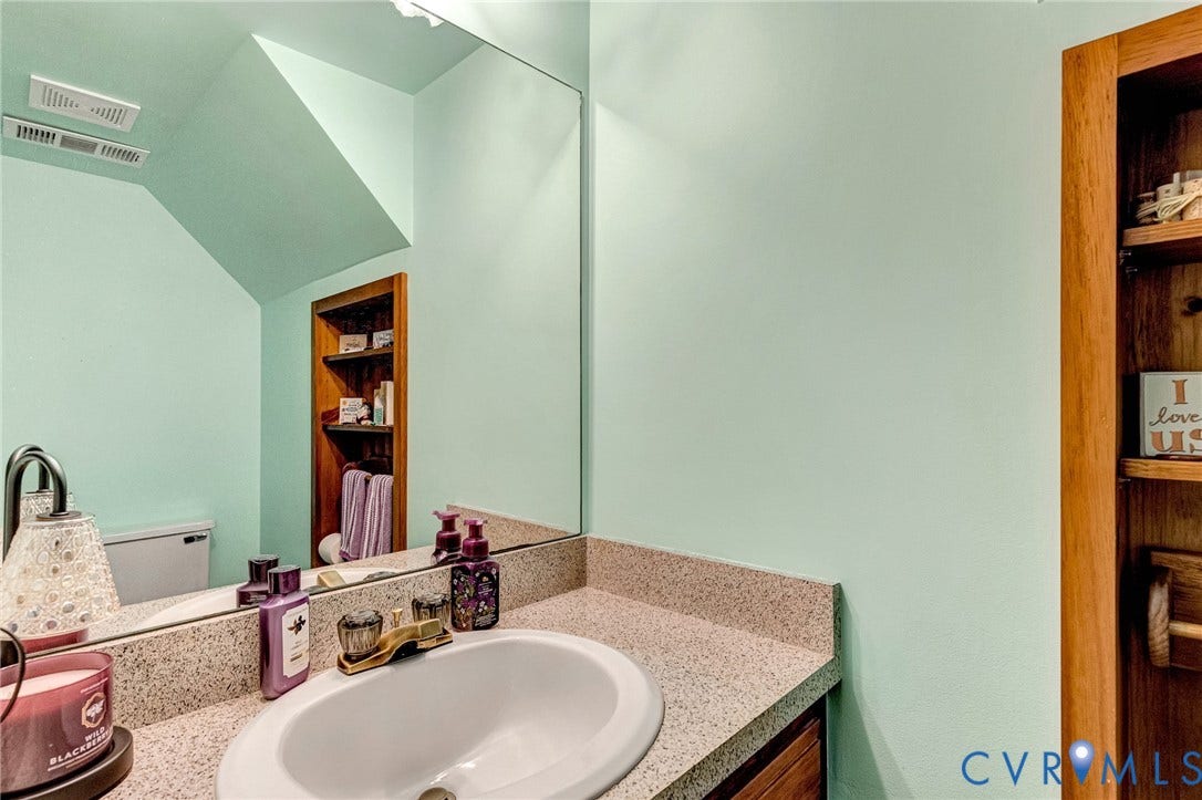 Vanity with integrated sink, speckled countertop, and wood-finish cabinetry