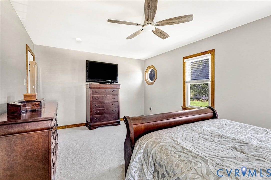 Light-colored wall paint with carpet flooring, a ceiling fan, and wood-trimmed windows