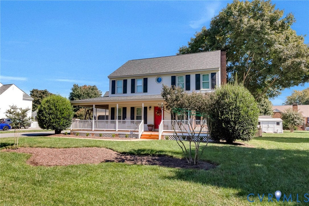 Two-story colonial residence with a covered front porch, white railings, and a red entry door