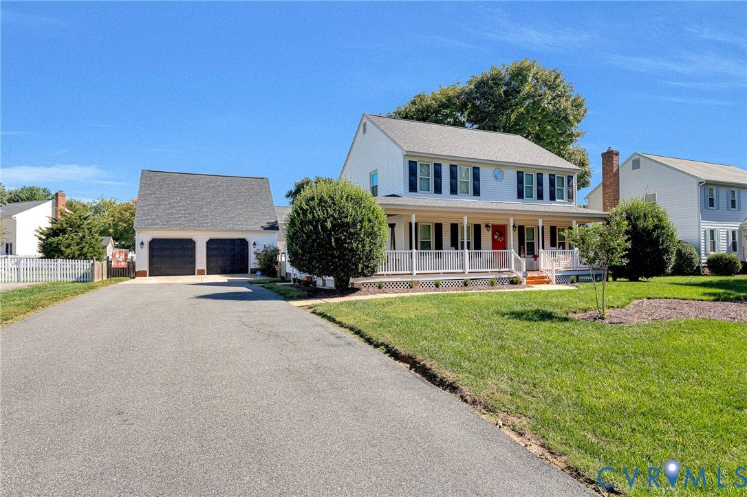 Two-story residence with a covered porch, white picket fence, and detached two-car garage