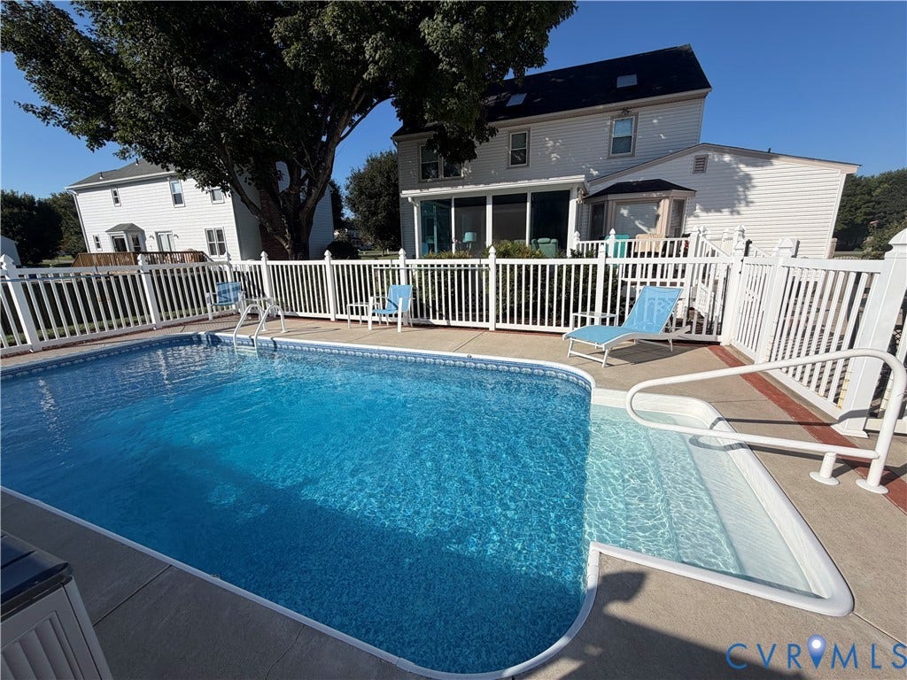 In-ground swimming pool with integrated steps, concrete surround, white vinyl fence enclosure, and a screened-in porch
