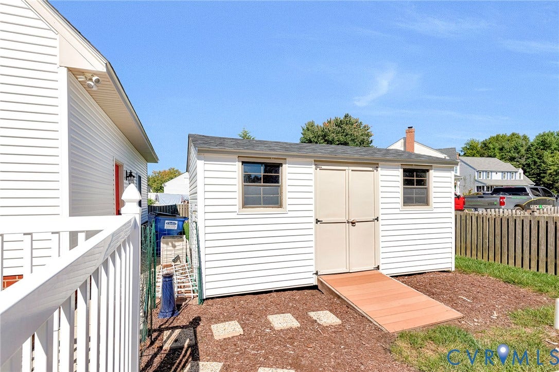 Exterior storage shed with dual doors, two windows, and a wood-finish ramp