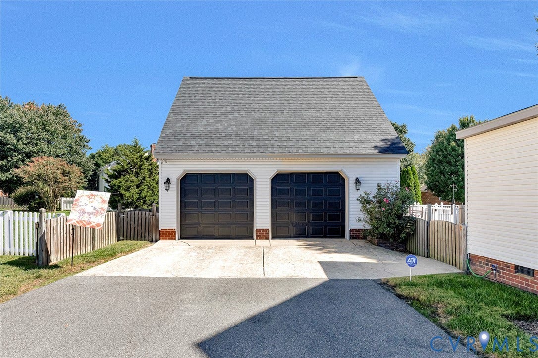 Two-car garage with panel doors, exterior wall lanterns, and a shingled roof