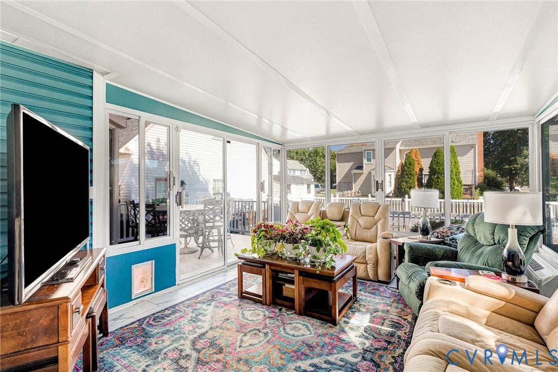 Sunroom with multiple large windows, a full-light sliding glass door, white ceiling panels, and a painted accent wall
