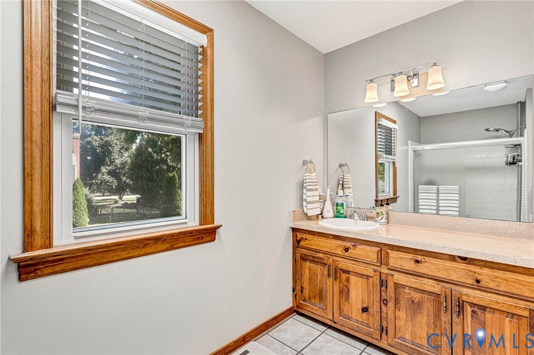 Vanity with wood cabinetry, integrated sink, and light-toned countertop