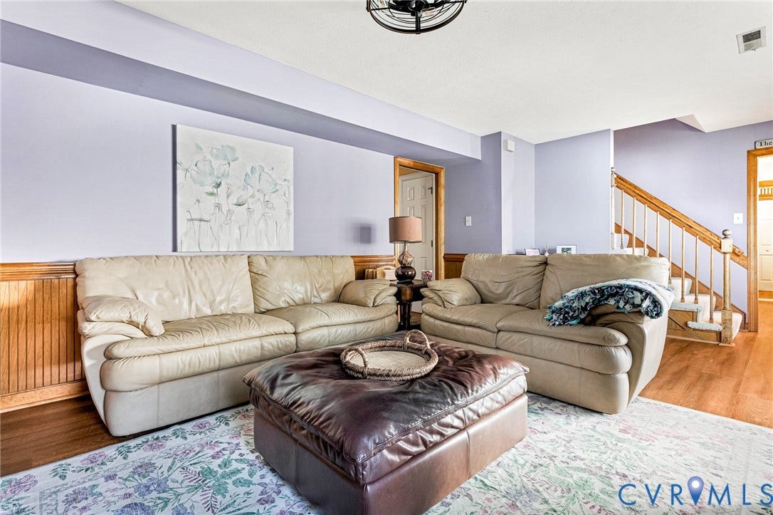 Wood-finish flooring, half-wall beadboard paneling, and a staircase with natural wood handrails and white balusters