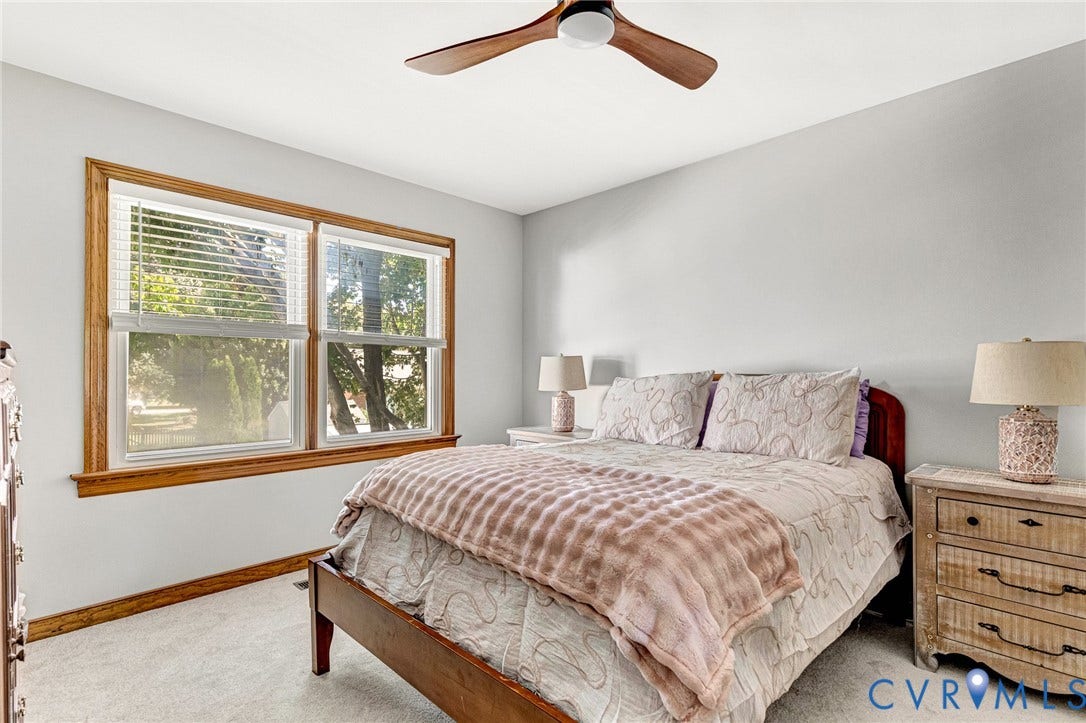 Light gray wall paint, wood-finish window trim, ceiling fan with wood-finish blades, and carpeted flooring