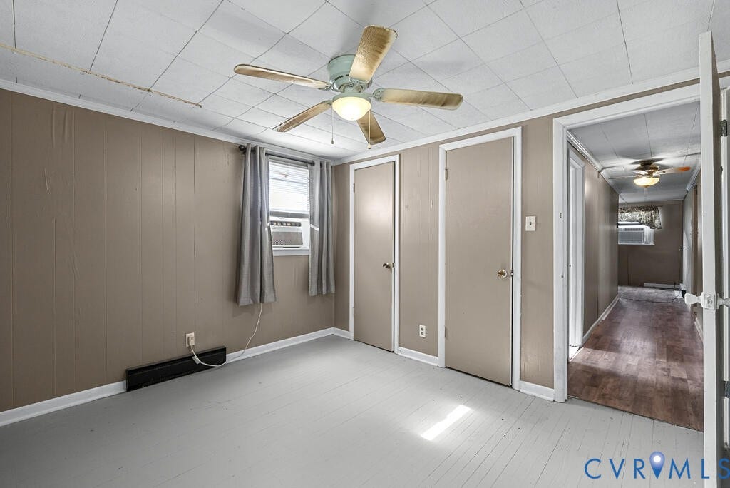 21 Vanderpool Lane, Detached, Cumberland, VA 23040 Wood-panel wall, window with an air conditioning unit, ceiling fan, and two closed panel doors