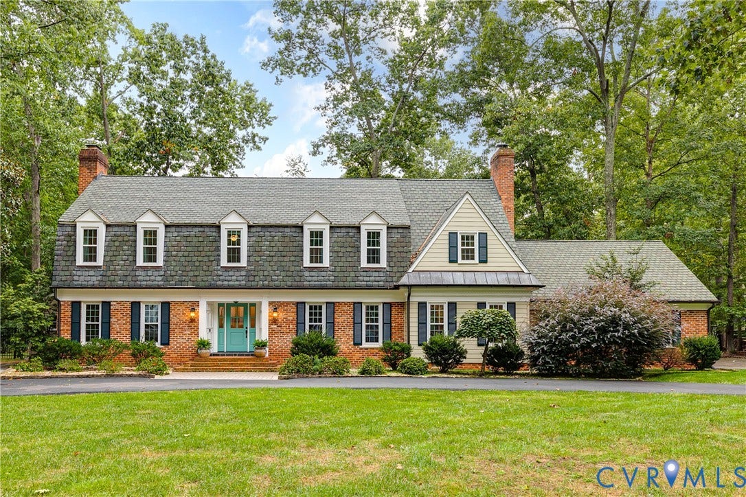 13619 Solstice Close, Salisbury, Midlothian, VA 23113 Brick exterior with a gray shingle roof and dormer windows, featuring a teal front door, dark shutters, and a mature tree-lined setting