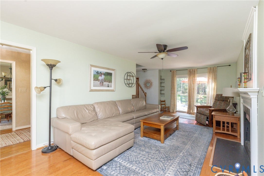 13802 Rockhaven Drive, Thornhill, Chester, VA 23836 Hardwood flooring, ceiling fan with integrated lighting, built-in shelving, white fireplace surround, and exterior access via sliding glass doors
