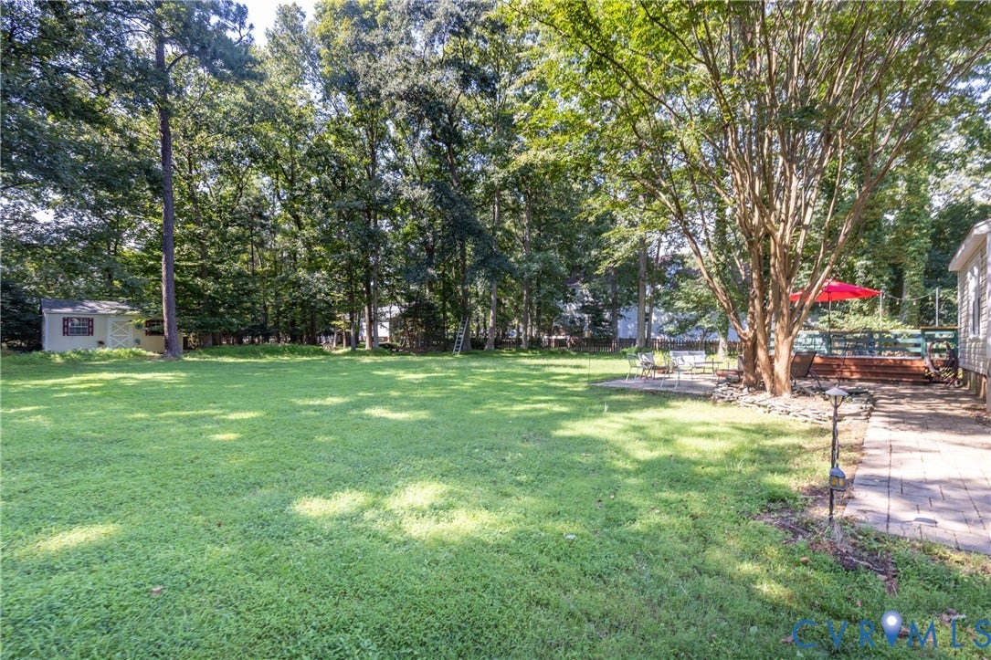 13802 Rockhaven Drive, Thornhill, Chester, VA 23836 Expansive lawn featuring mature trees, a wood deck, a patio area, and a detached storage shed