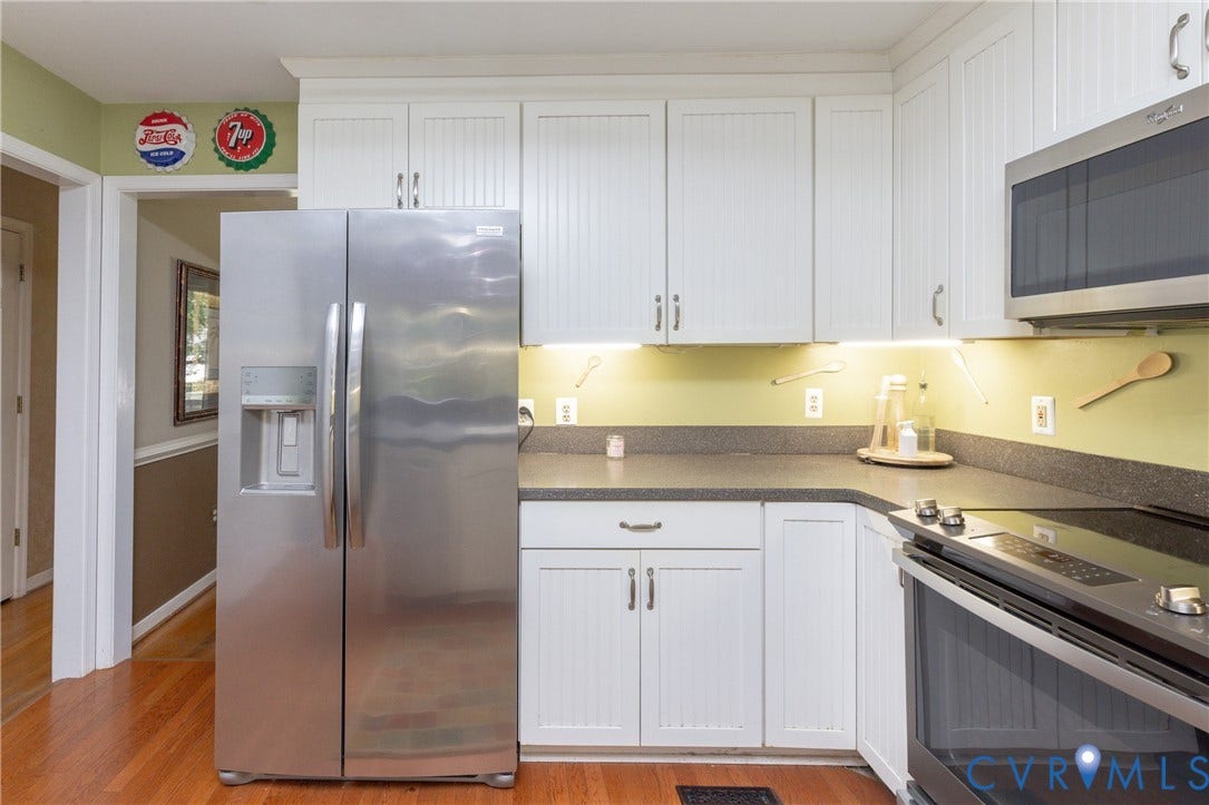 13802 Rockhaven Drive, Thornhill, Chester, VA 23836 Kitchen featuring white beadboard-style cabinetry, dark countertops, a stainless steel side-by-side refrigerator, a stainless steel microwave, and wood-finish flooring