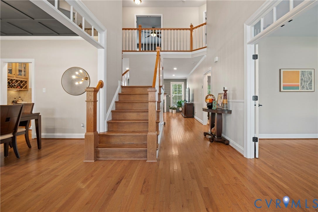 Two-story foyer featuring wood flooring, a wood staircase, and a second-story landing with white balusters