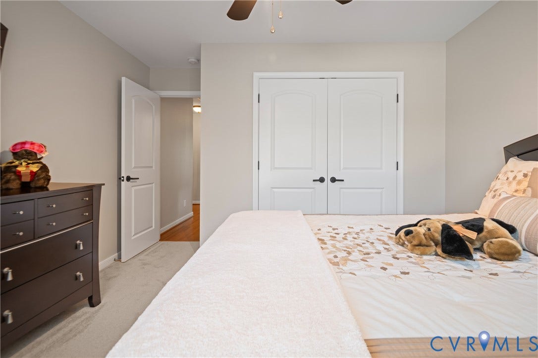 Neutral wall color, carpeted flooring, white interior door, and double white closet doors with dark hardware
