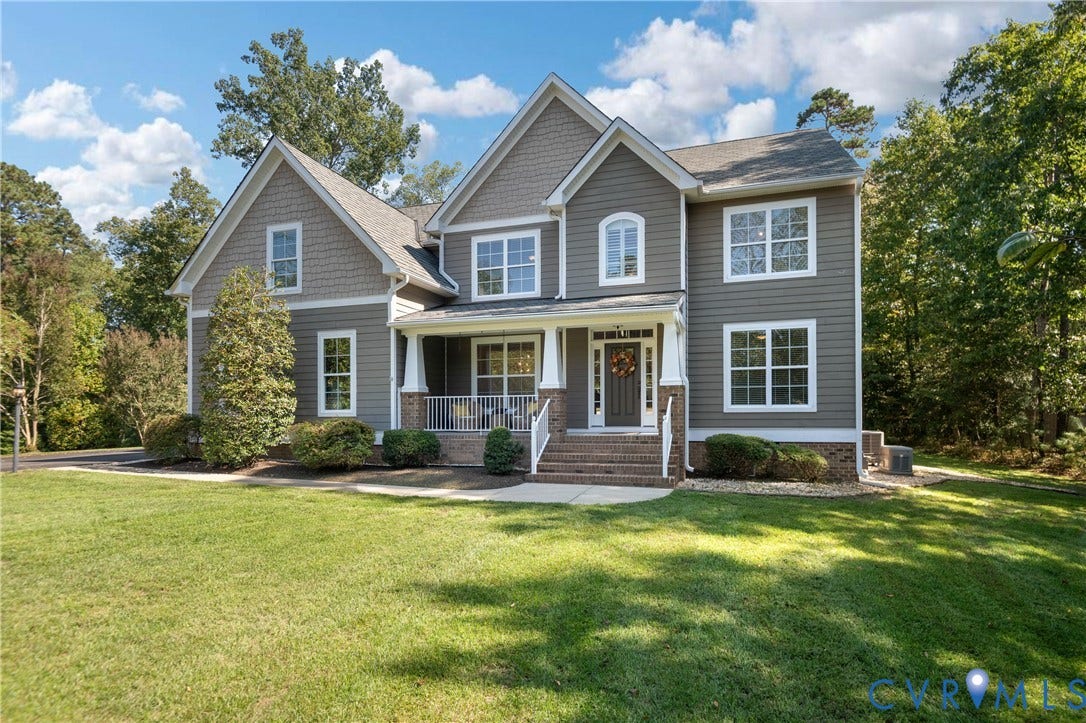 Two-story residence featuring a covered front porch, gabled rooflines, and a brick foundation