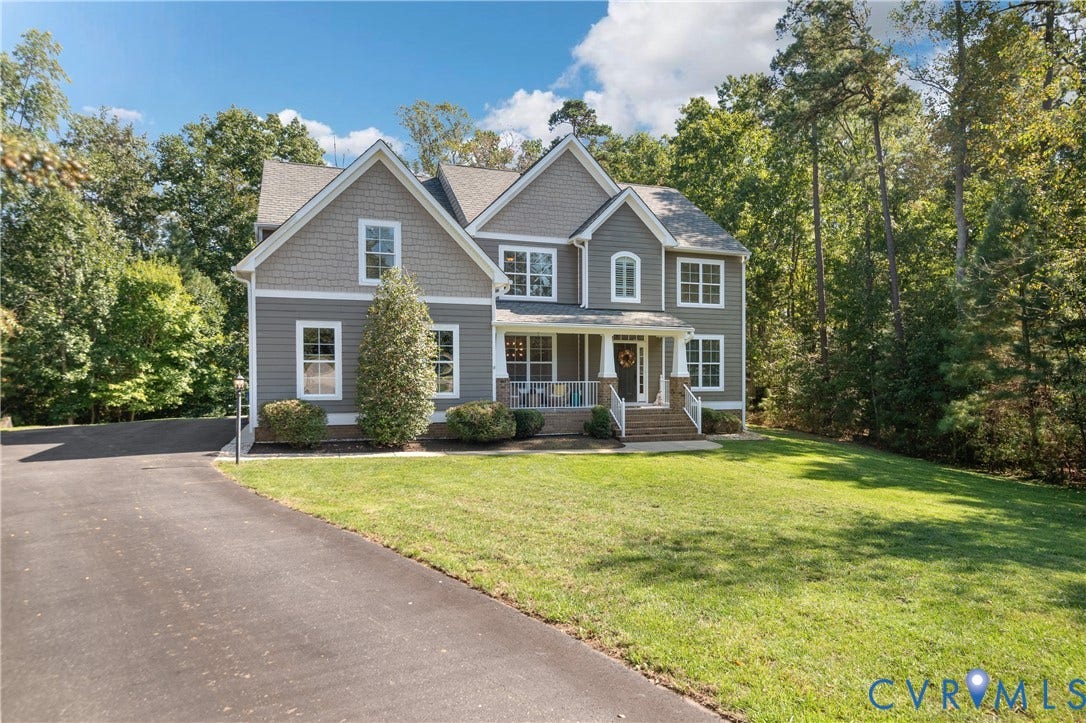 Two-story residence featuring a covered front porch, gabled rooflines, and a paved driveway