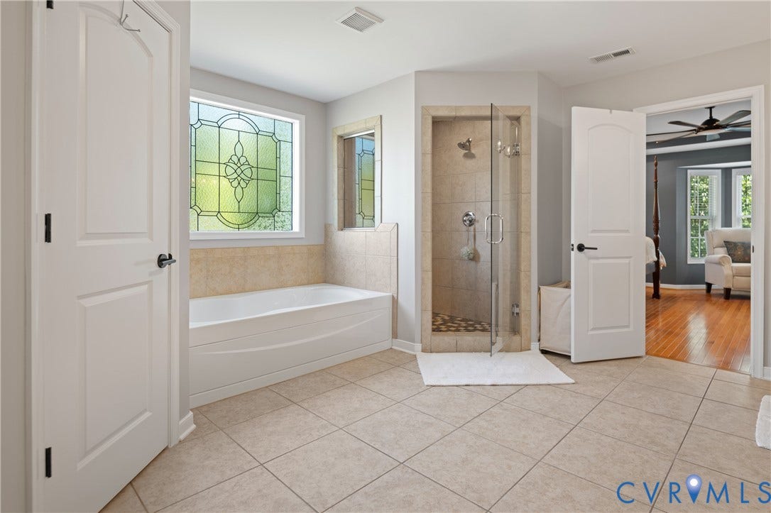 Spacious bathroom featuring a built-in bathtub, a walk-in shower with clear glass enclosure, and large format floor tiling