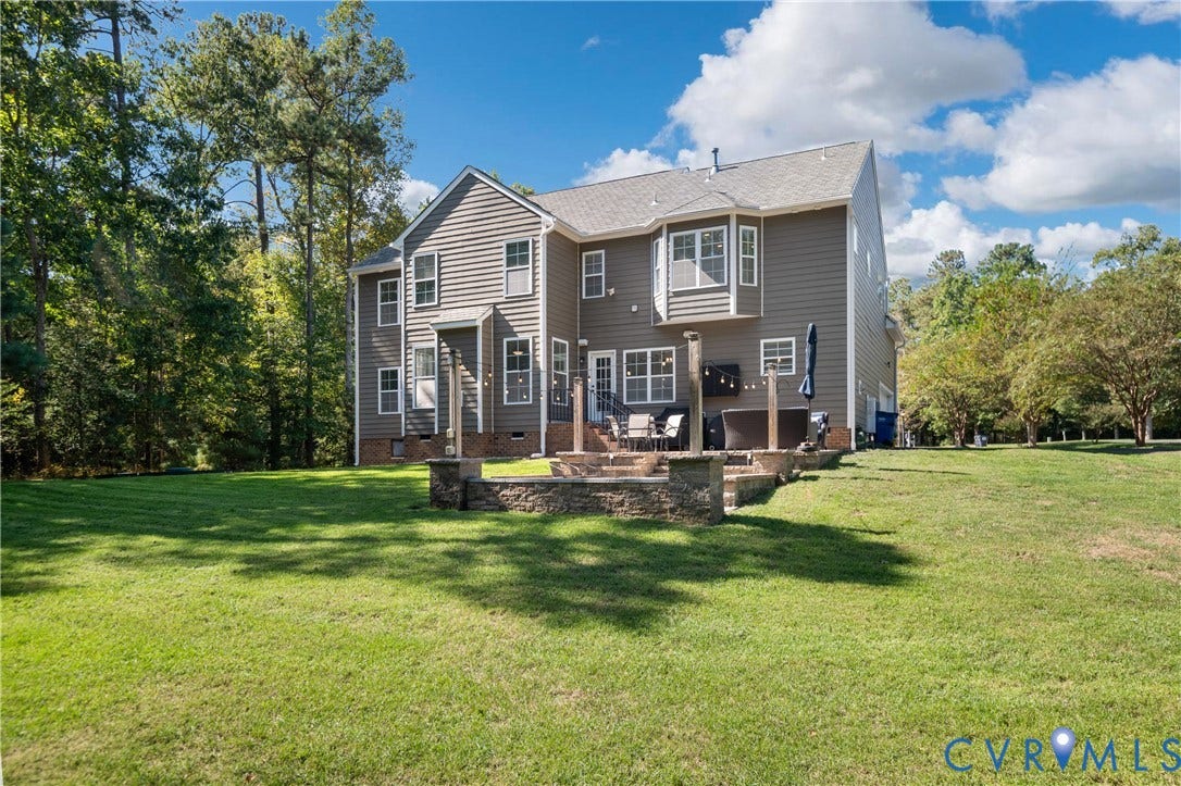 Multi-story siding exterior with a gabled roof, rear patio, and stone retaining walls
