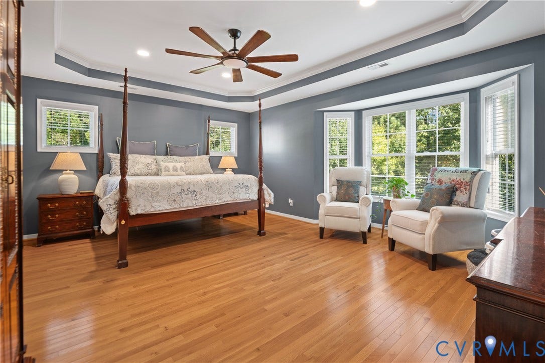 Hardwood flooring, tray ceiling, recessed lighting, ceiling fan, and bay window
