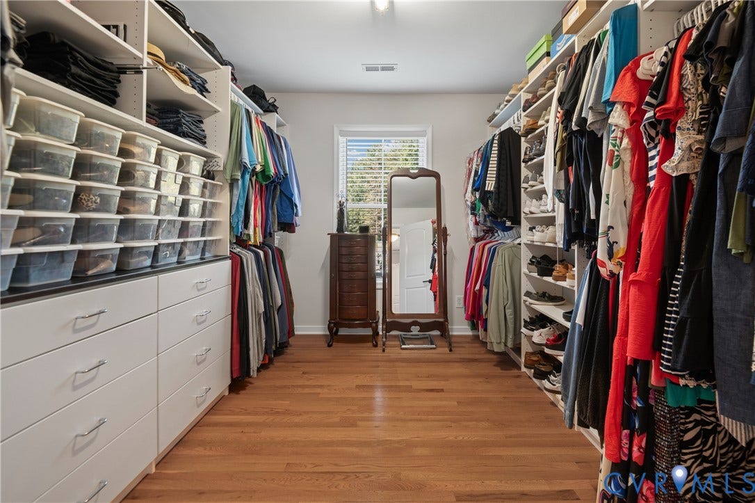 Built-in custom closet system with white cabinetry, wood-finish flooring, recessed lighting, and a window with blinds