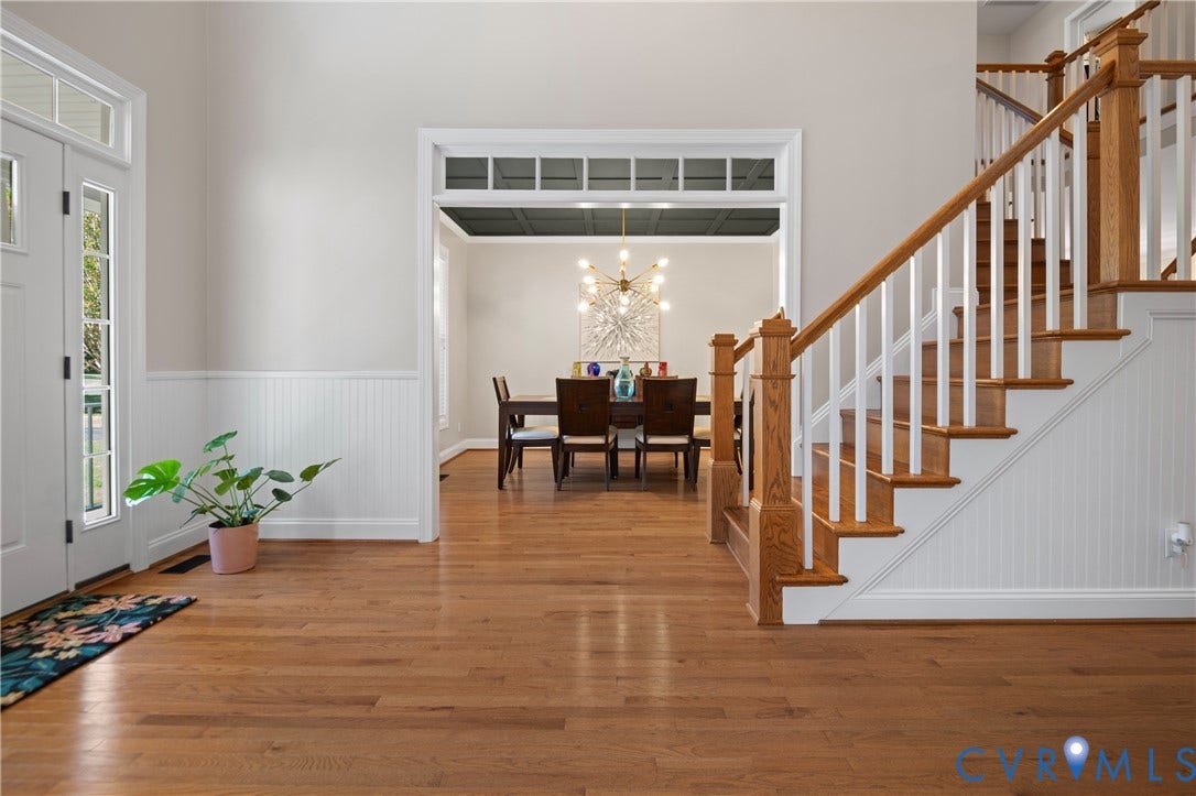 Hardwood flooring, wainscoting, white trim, and a wood staircase with white balusters