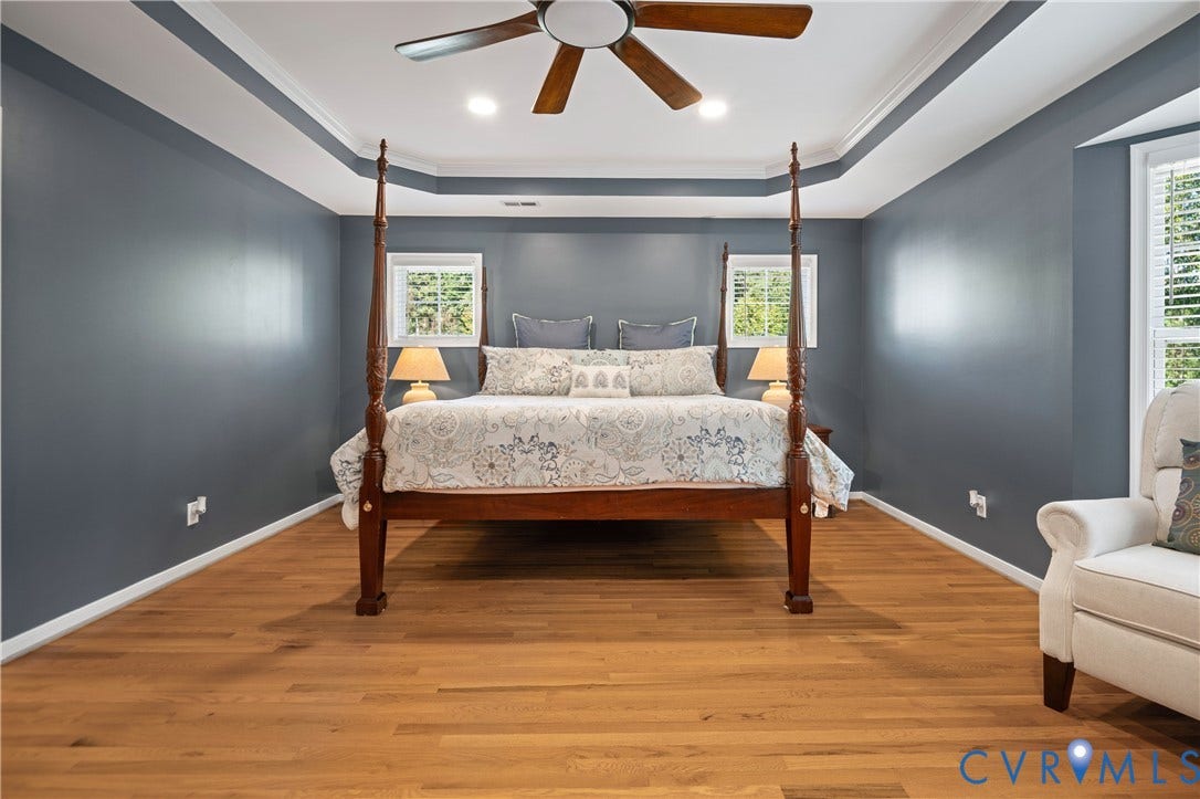 Tray ceiling with recessed lighting and a ceiling fan, wood-finish flooring, and multiple windows