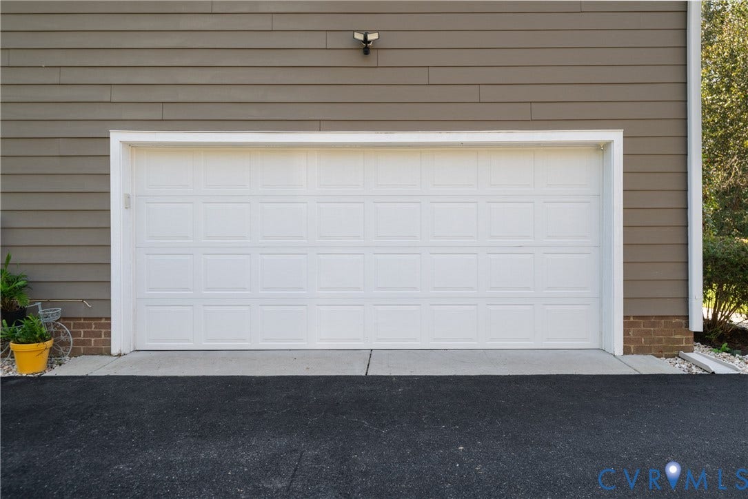 White panel garage door with a concrete approach and asphalt driveway