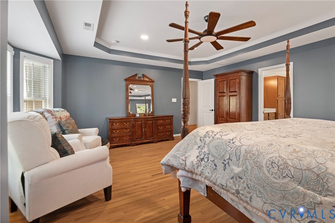Tray ceiling with a ceiling fan, light wood-finish flooring, recessed lighting, and multiple windows with blinds