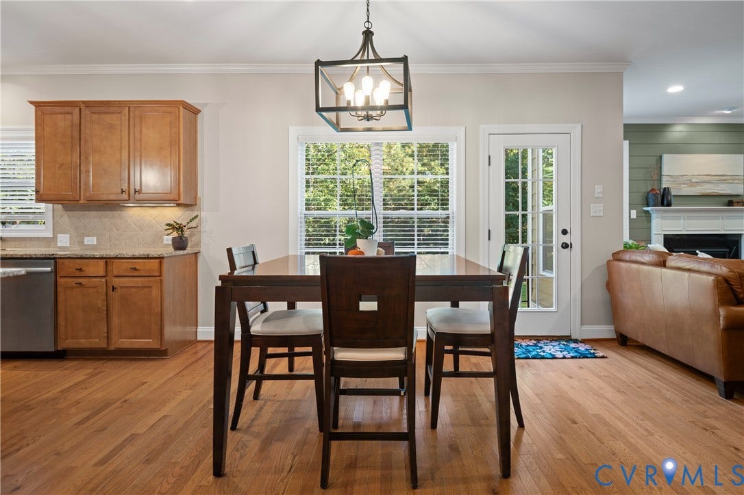 Hardwood flooring throughout, kitchen with wood cabinetry and tile backsplash, double casement windows, and a glass-paneled door