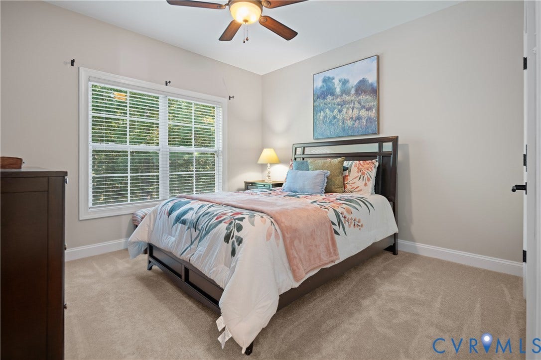 Carpeted bedroom featuring a ceiling fan with light fixture and a double window