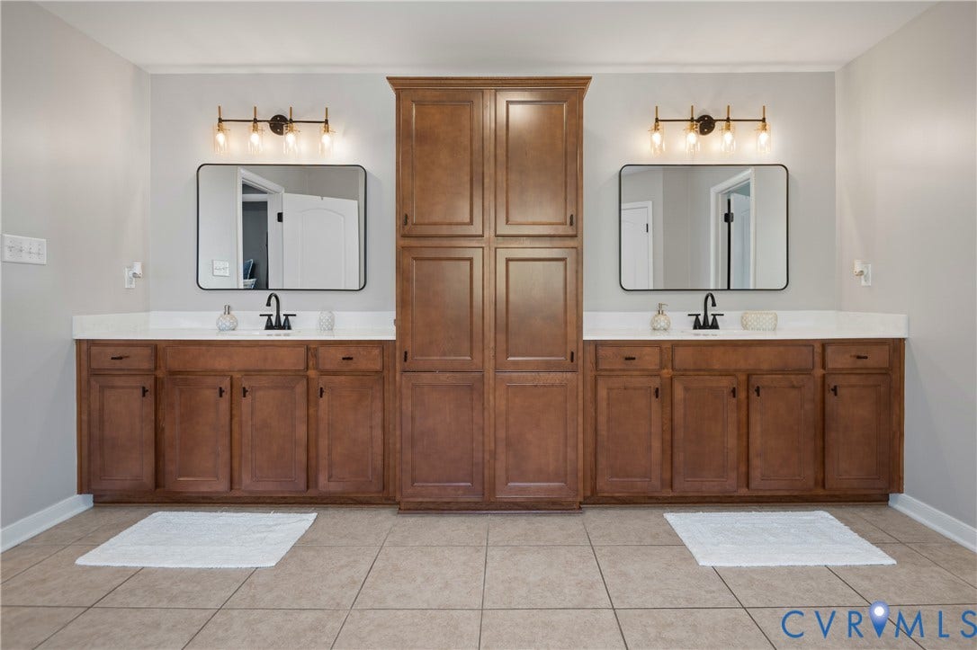 Dual vanities with white countertops, wood-finish cabinetry, and matte black fixtures