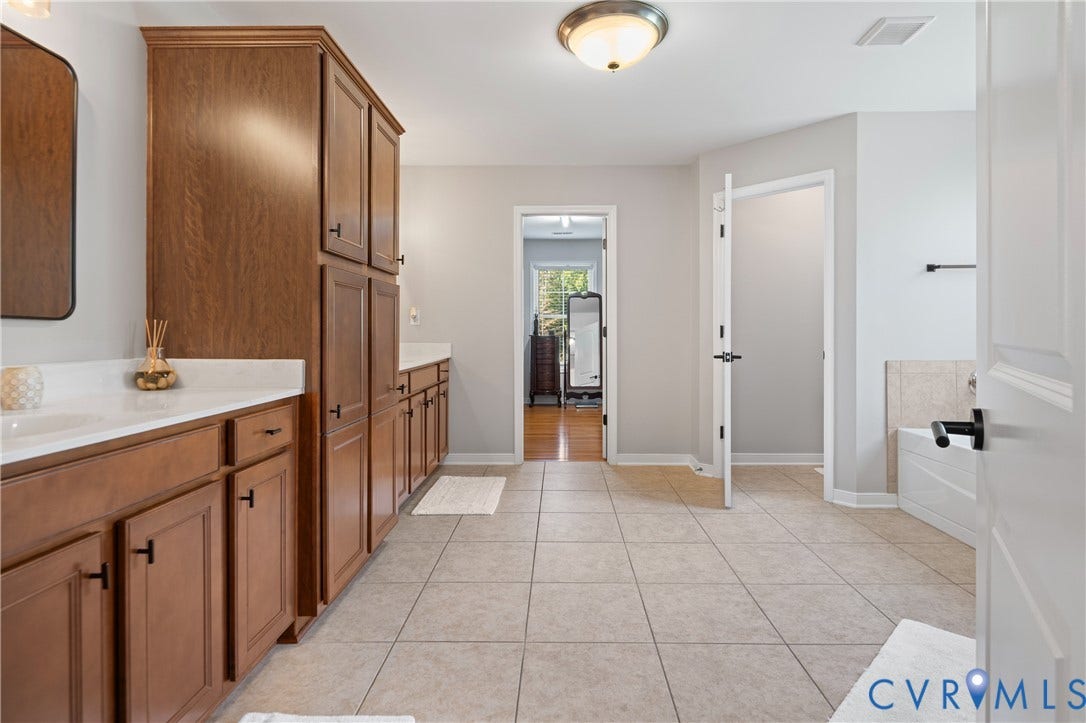 Dual wood-finish vanities with white countertops, integrated sinks, and dark hardware