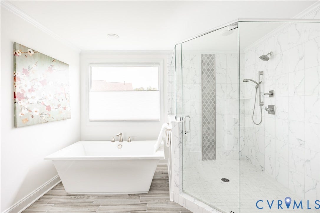 Spa-inspired primary bathroom featuring a freestanding soaking tub, large walk-in shower with frameless glass enclosure and dual showerheads