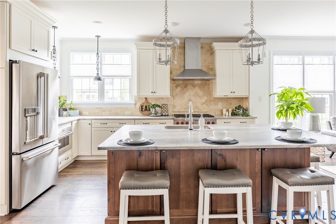 Large chefs kitchen with high end WOLF and Cafe appliances, oversized leathered granite island with seating and ample storage.
