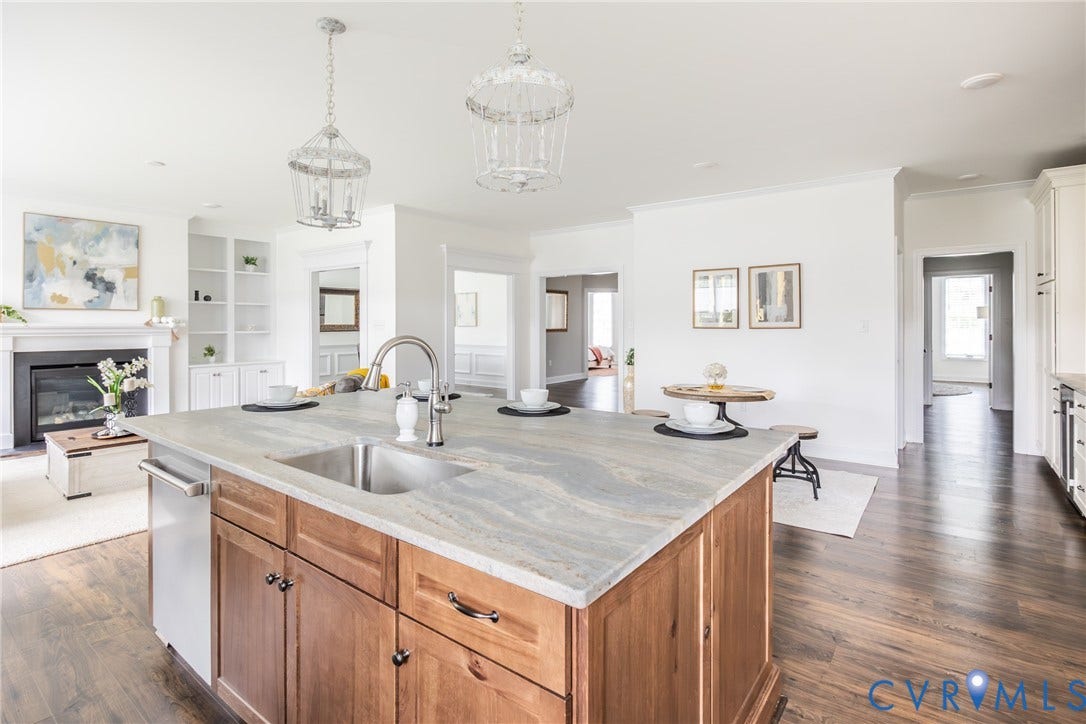 Alternate kitchen view of the leathered granite island with Delta motion faucet. The kitchen opens to the family room and to the right you see the hallway that leads to the dropzone, garage entrance and the front office.