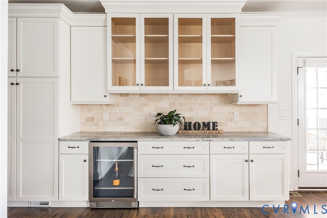 The owners thoughtfully added this kitchen bar space for storage and entertaining. All soft close doors and drawers with pull out shelving inside. The door to the screened patio is visible on the right.