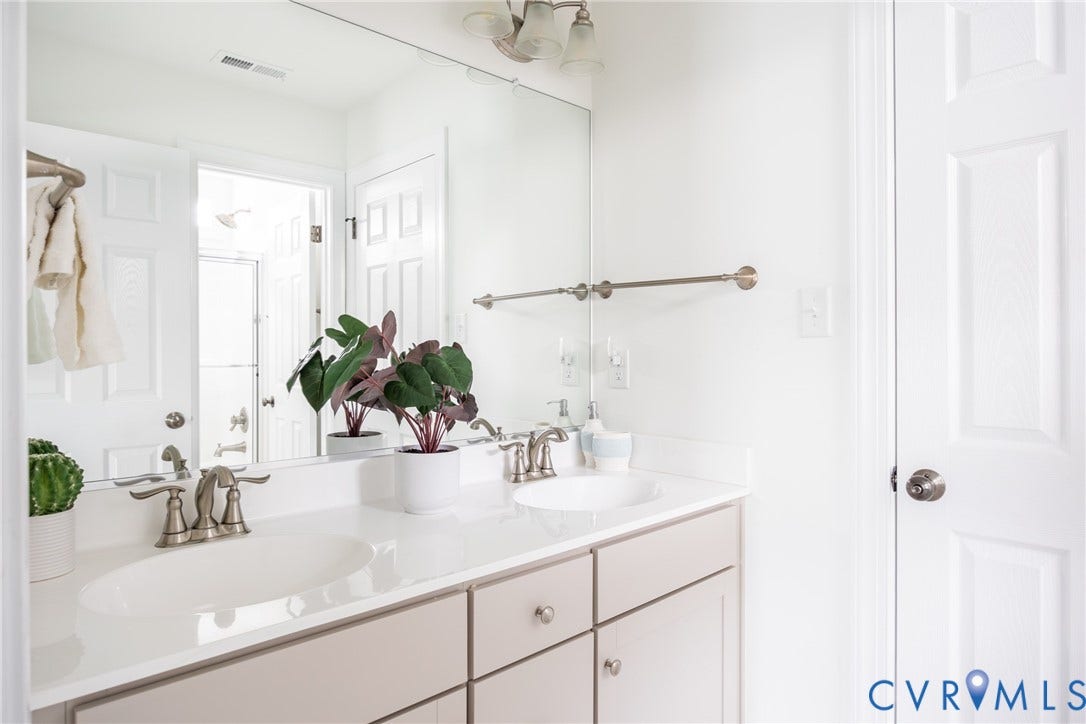 Full Jack and Jill bathroom with dual sink vanity and stainless steel fixtures.